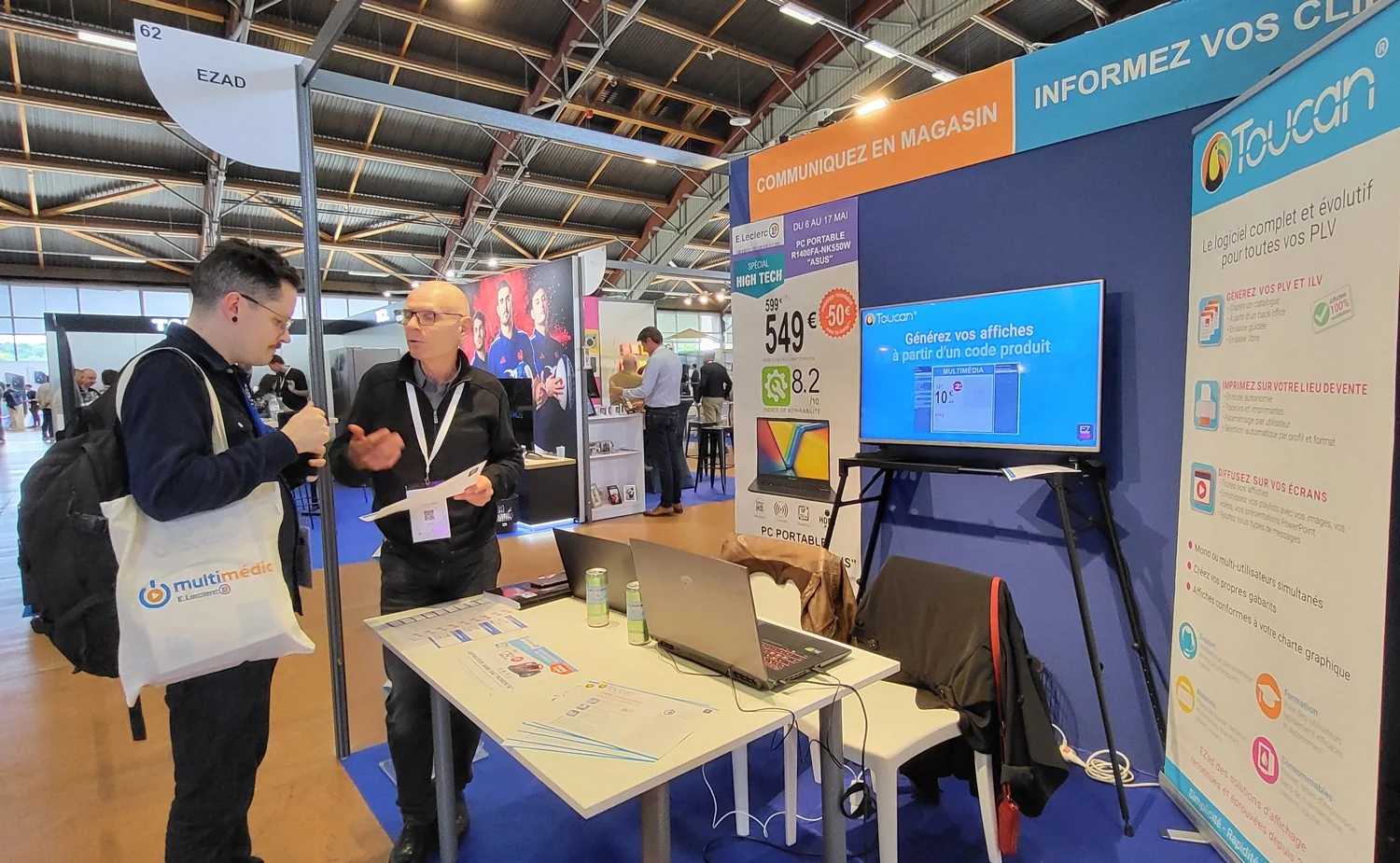 Stand EZad au salon BTLEC avec visiteur, écran de présentation, grandes affiches et kakémono Toucan