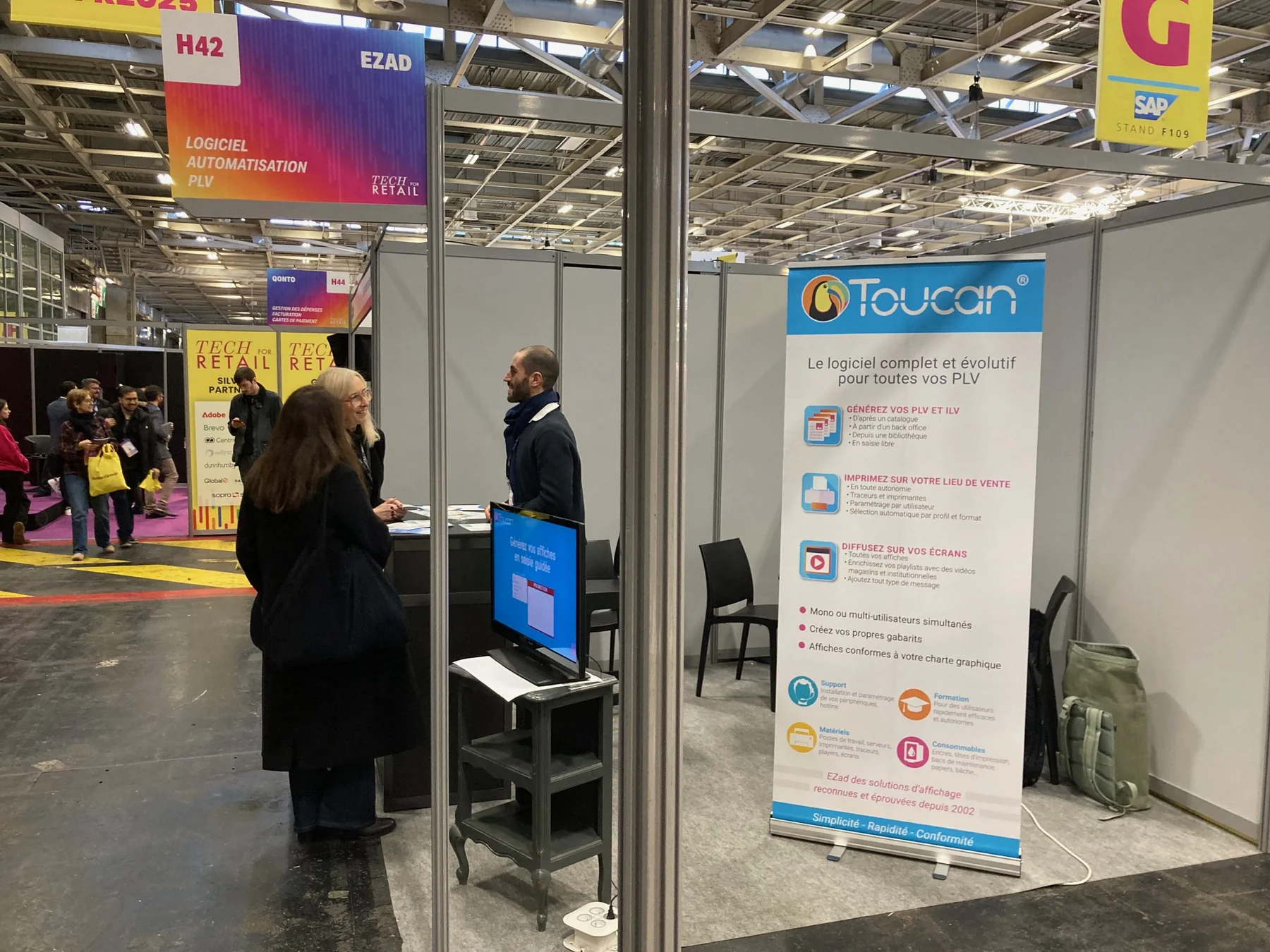 Stand EZad au salon Tech for Retail 2025 avec kakémono Toucan, écran et visiteurs